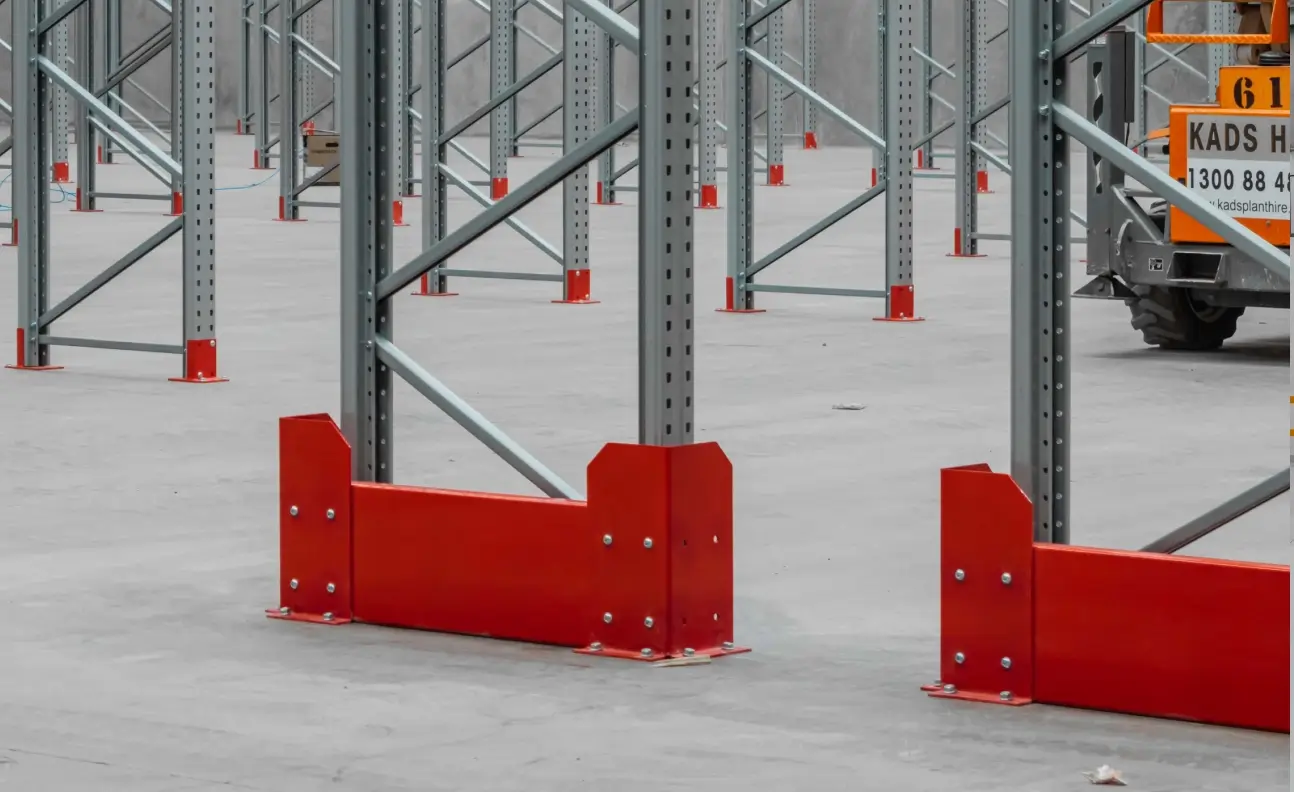 Red corner protectors installed on pallet racking uprights to prevent forklift impact damage